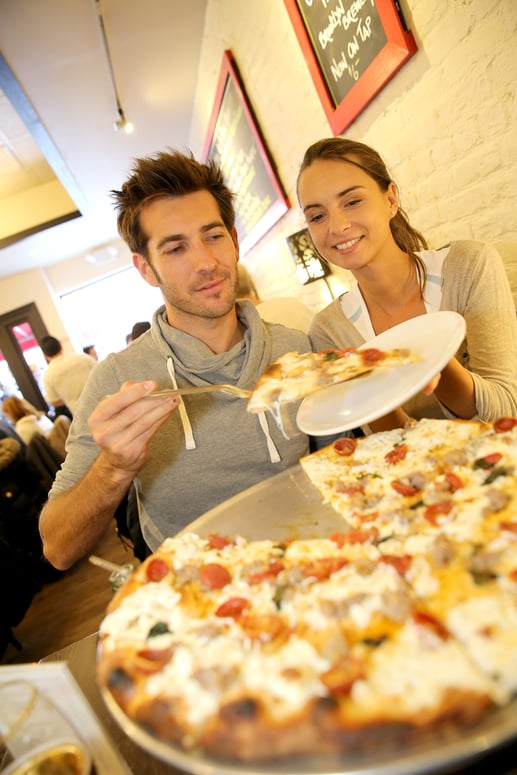 A couple eating pizza at a local pizzeria.